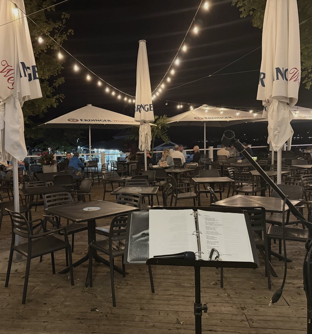 Waterfront patio under string lights at night, seen from the microphone